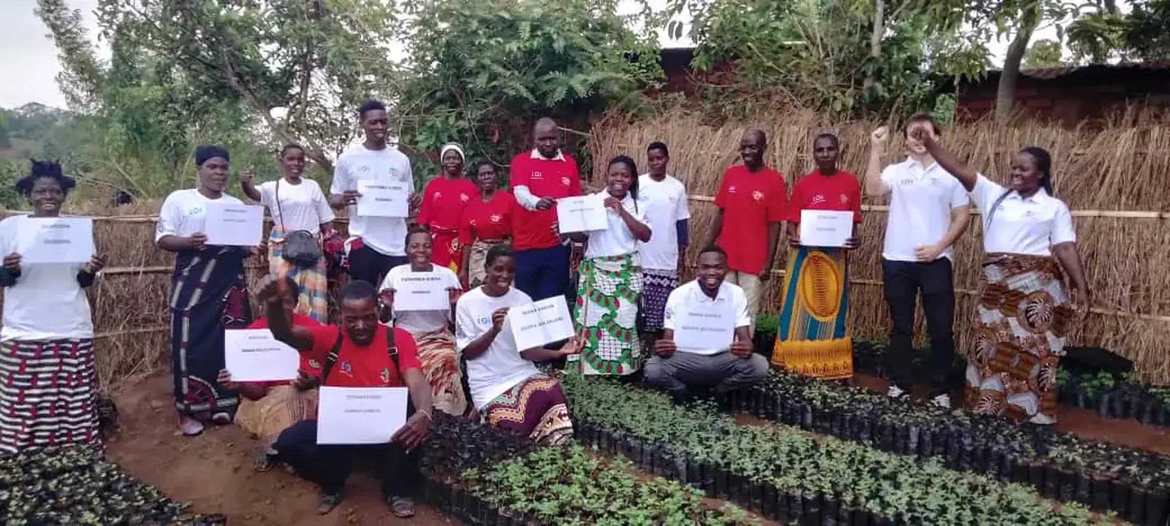 Project cohort members holding certificates beside nursery seedlings