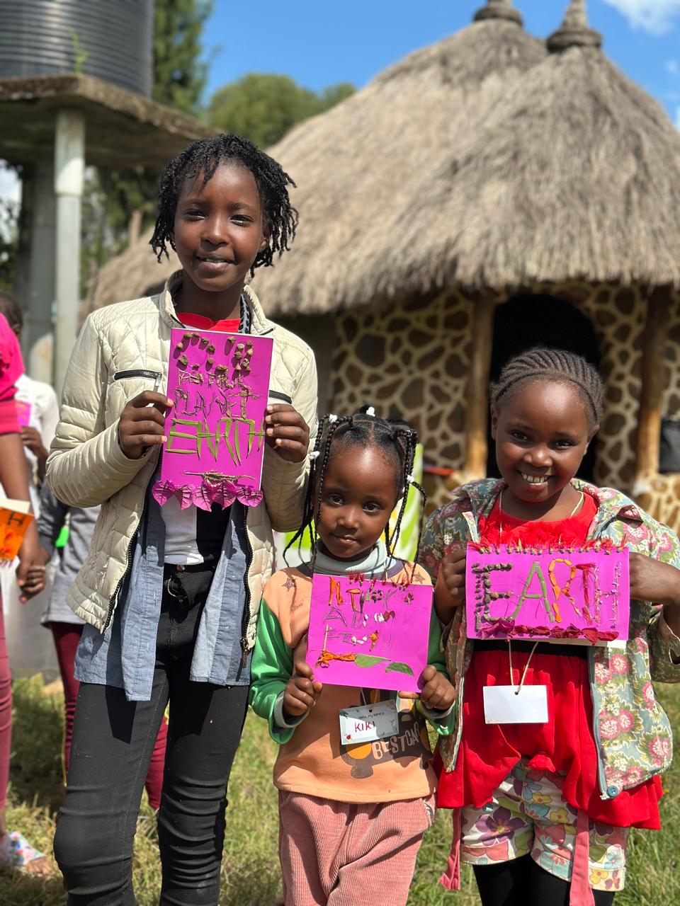 Three children displaying their nature-inspired artwork at Light On A Hill
