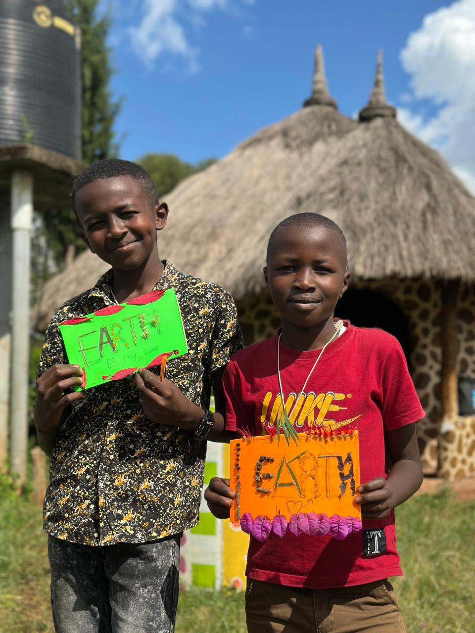 Two children displaying green and orange Earth artwork at Light On A Hill