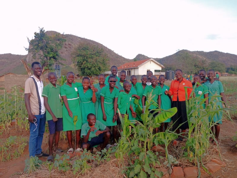 Students and adults gathered among crops in a school garden